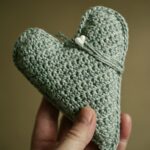 grey handmade unique love shaped crochet peice held in hand