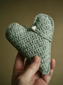 grey handmade unique love shaped crochet peice held in hand