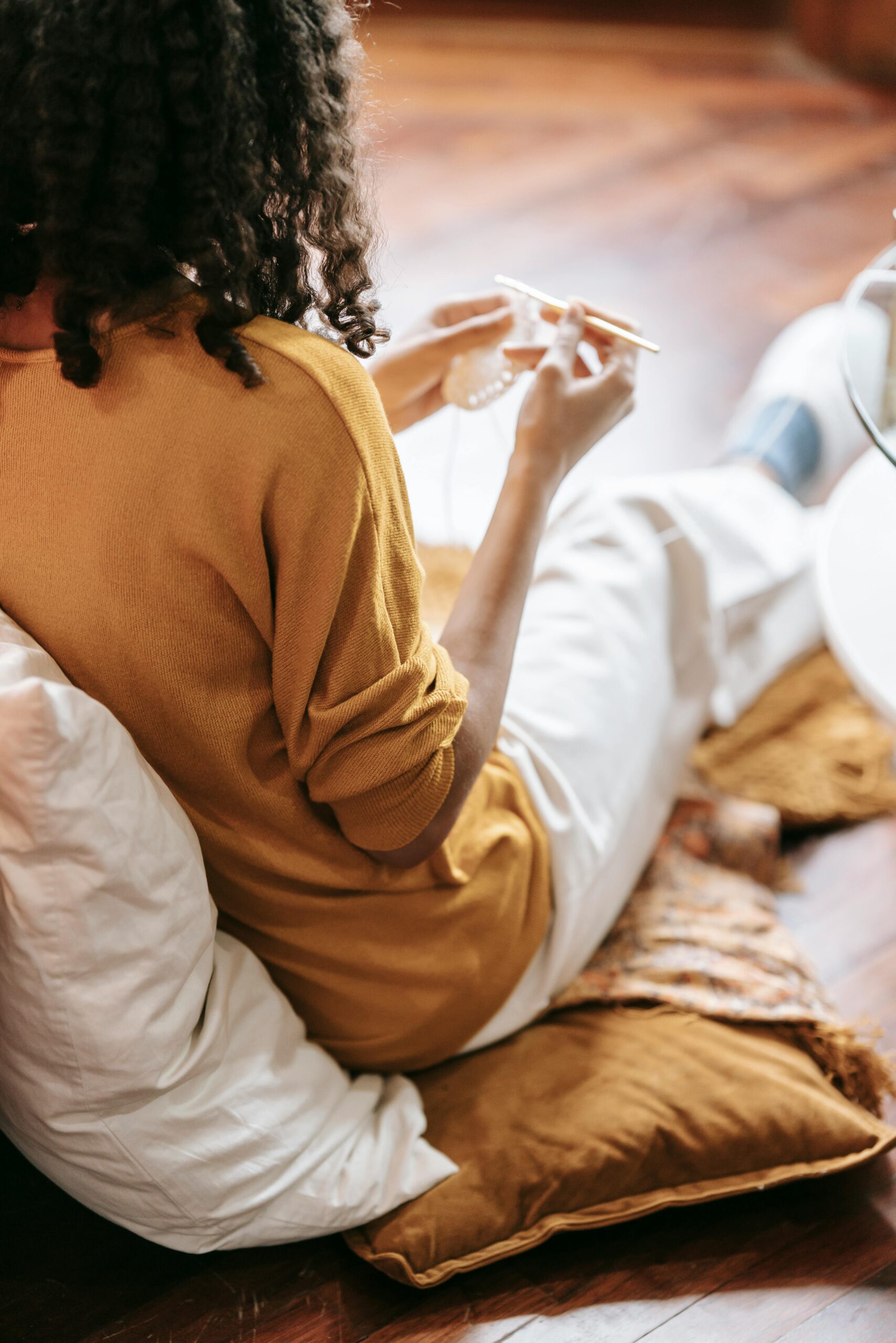 A woman with curly hair crocheting costumized crochet indoors, embodying relaxation and creativity.